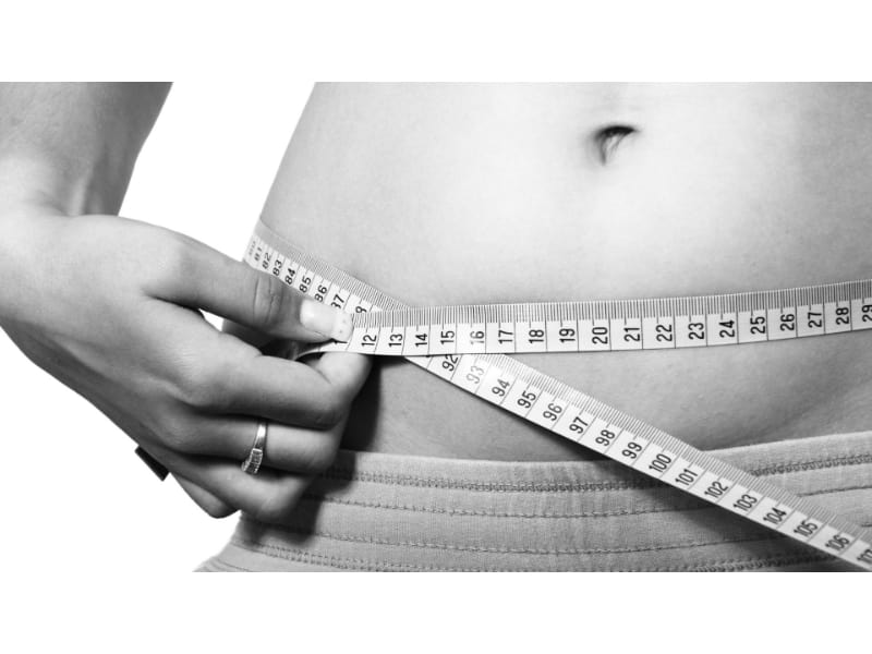 Woman measuring her waistline using a tape measure