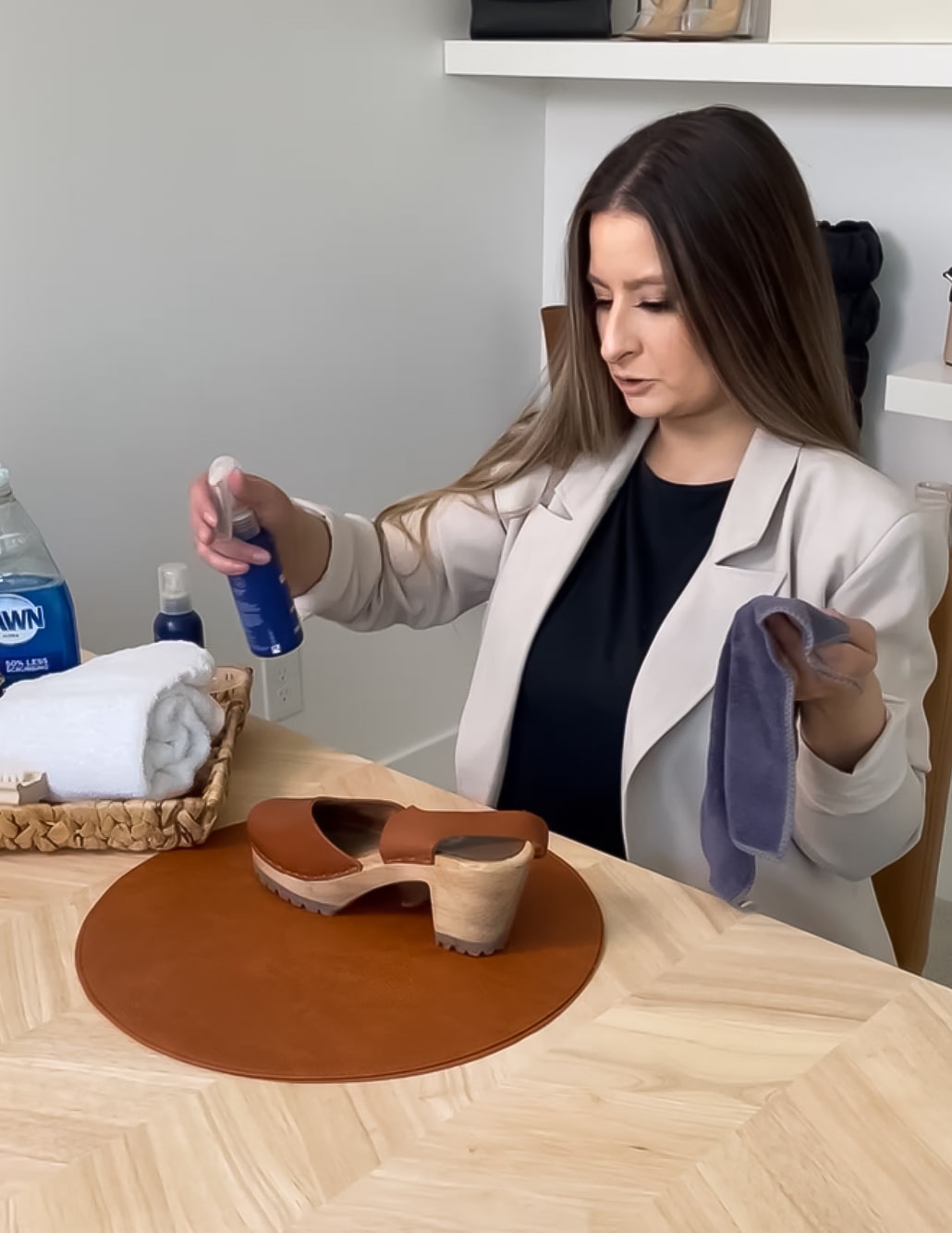 brunette spraying leather protectant on shoes