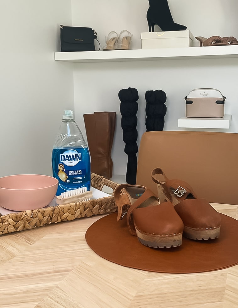 brown clog on table next to dish soap and small pink bowl