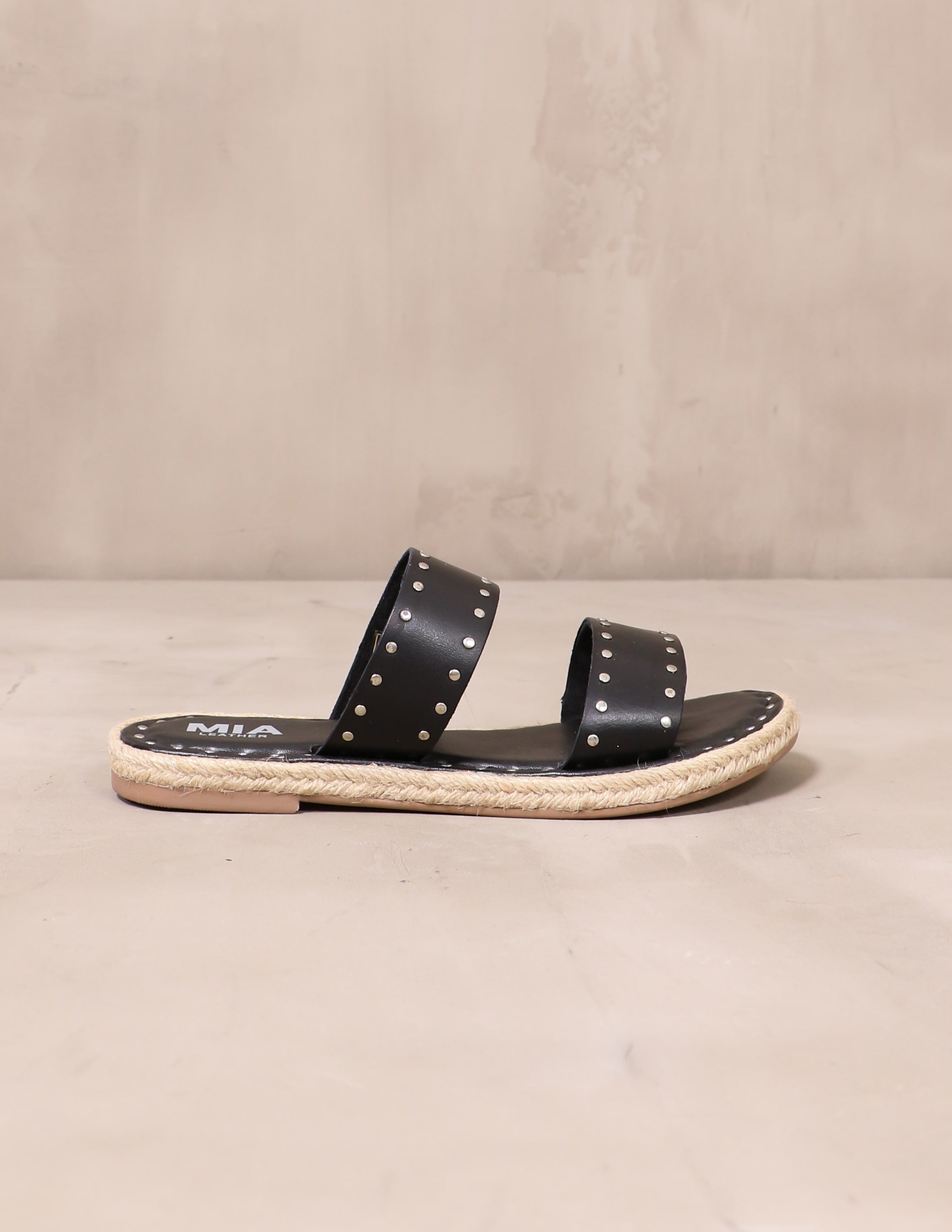 black let the stud times roll sandal on cement background