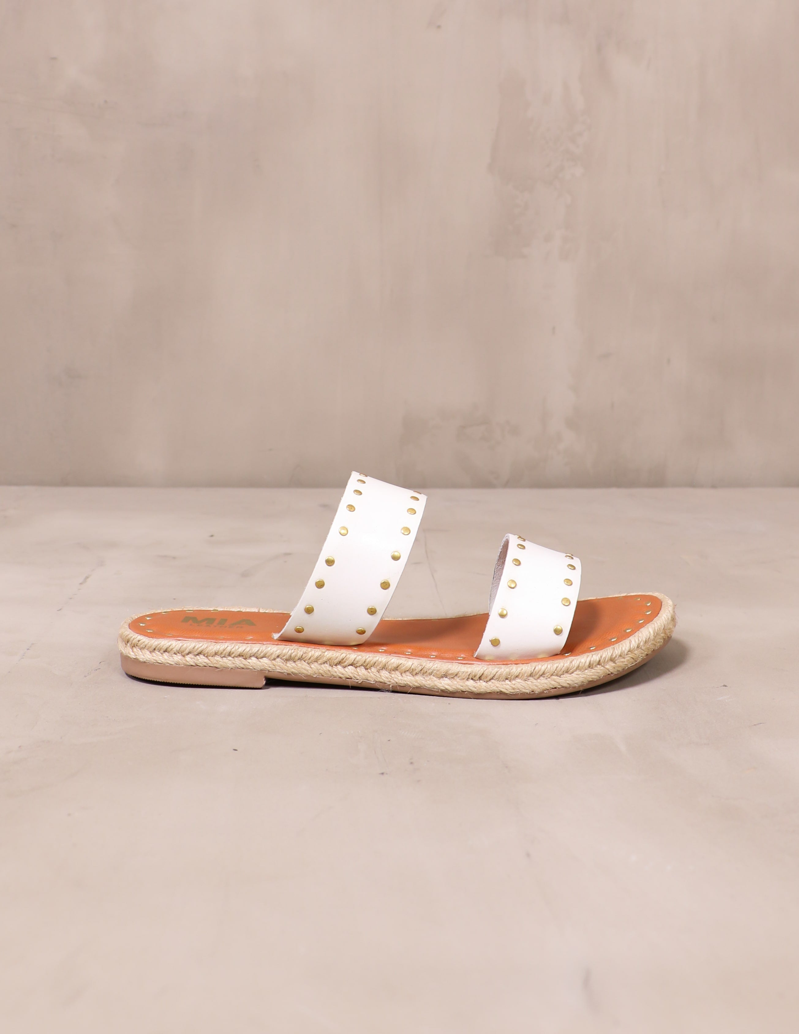 white let the stud times roll sandal on cement background