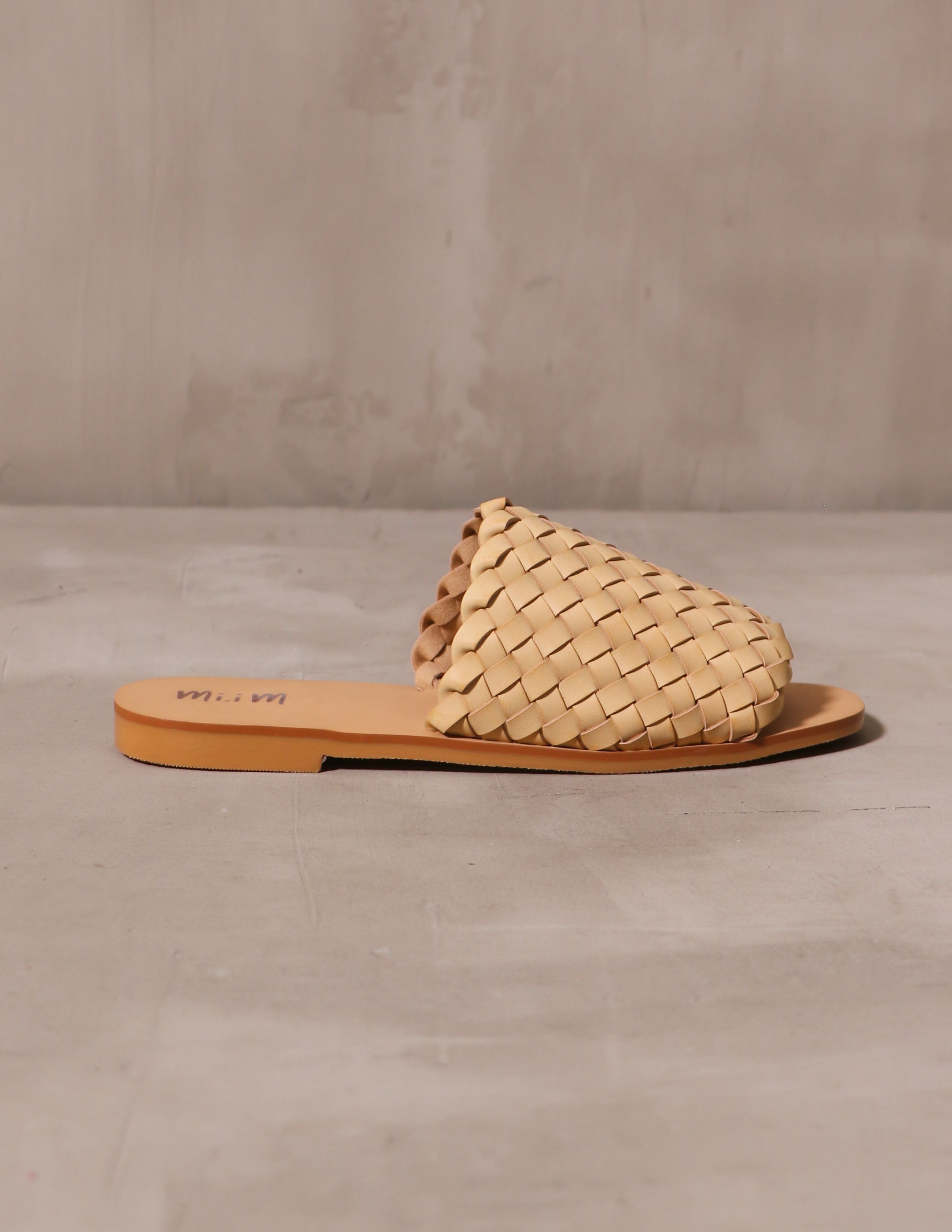 beige woven one slide sandal on cement background