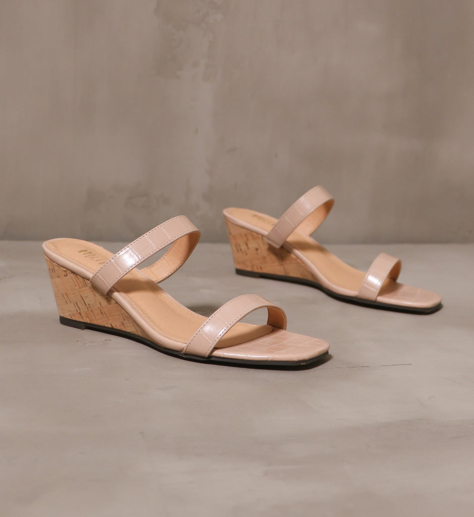 close up of the pair of rose colored kim and cork take new york wedges angled on cement background