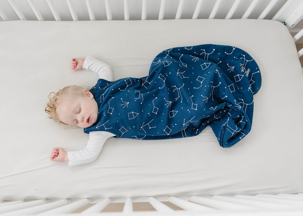 Baby asleep in crib wearing a Woolino 4 Season® Basic merino wool Sleep Bag in Night Sky print