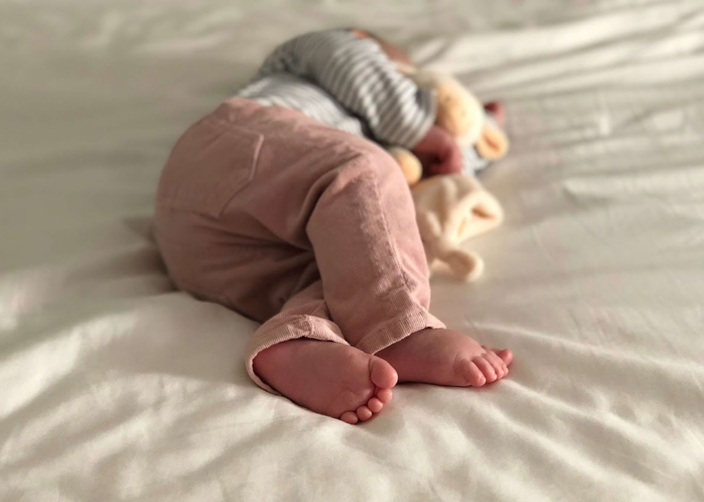 Baby lying on its side, in bed, hugging teddy bear whilst asleep. Baby Twitching In Sleep.