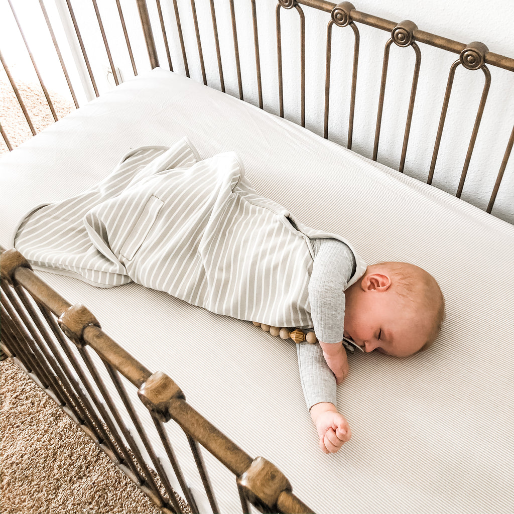 Baby sleeping in crib wearing a Woolino 4 Season Ultimate Baby Sleep Bag in Birch Gray.