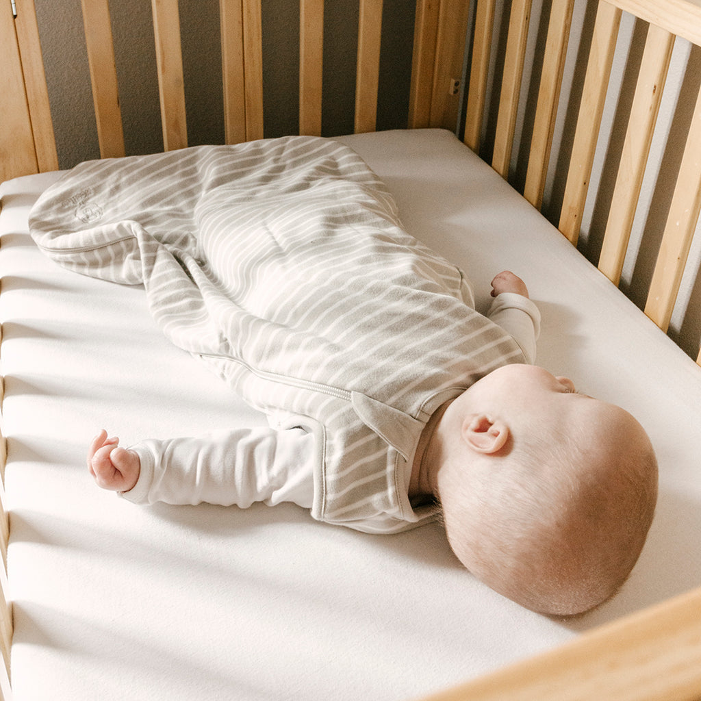 Baby sleeping on back in crib wearing a Woolino merino wool sleep bag