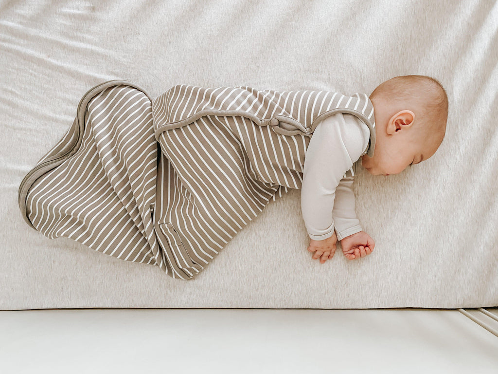 Baby sleeping on side in a Woolino sleep sack.