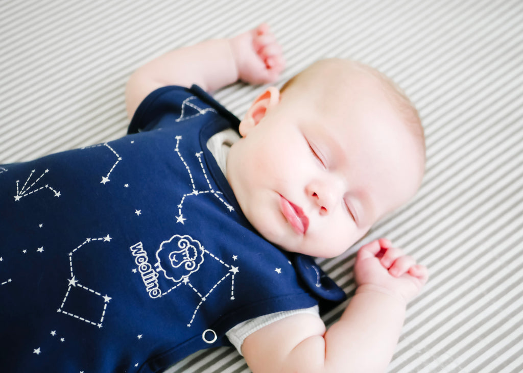 Baby sleeping peacefully in a Woolino 4 Season® Ultimate Baby Sleep Bag in Night Sky print