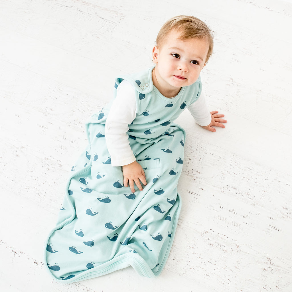 Baby wearing a Woolino 4 Season® Ultimate merino wool Baby Sleep Bag in Whales print