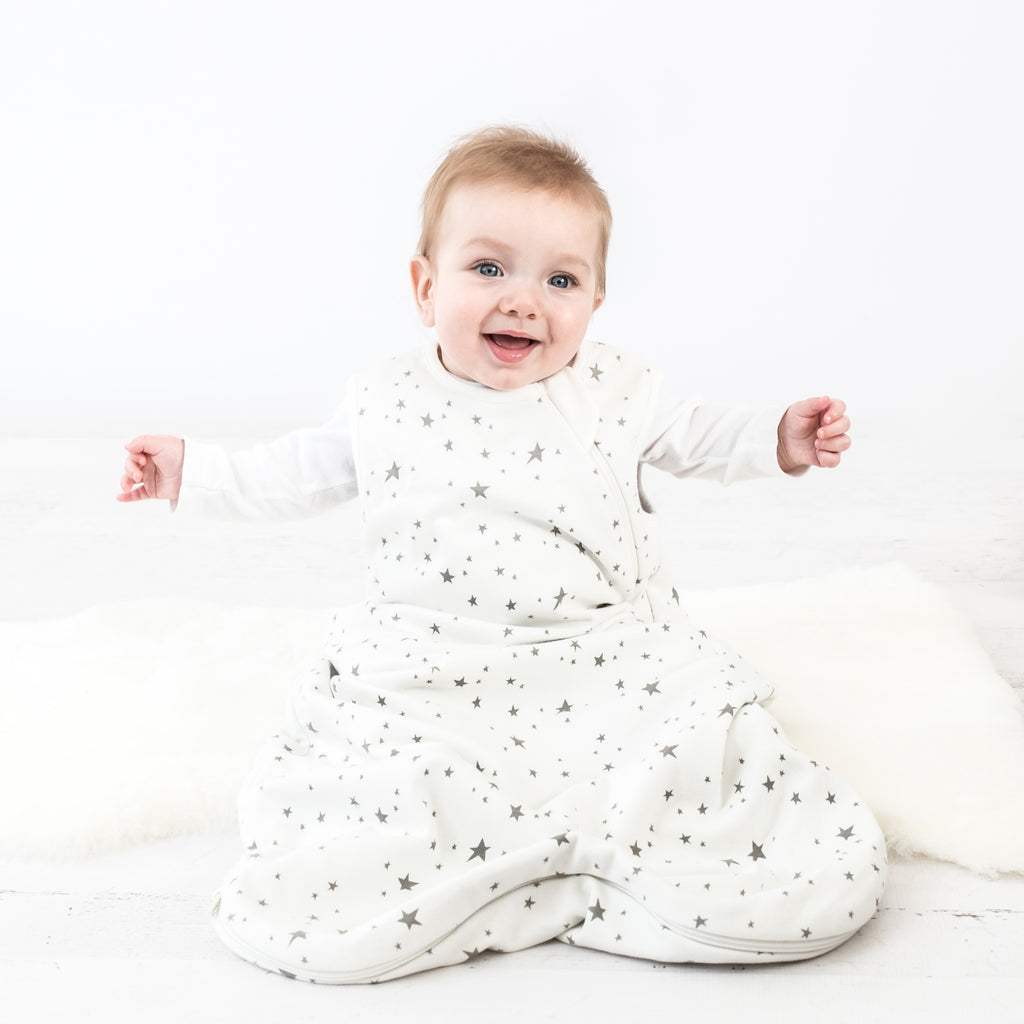 Smiling Baby sitting up wearing a Woolino 4 Season® Basic Baby Sleep Bag in Stars print