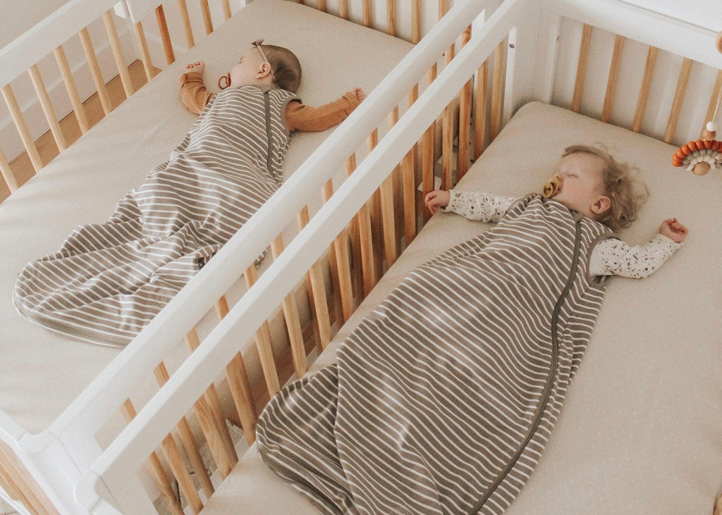 Twin babies sleeping on their backs in Woolino sleep sacks