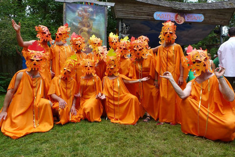 A group of 15 to 20 people dressed up in bright solid orange robes with fire masks on.  