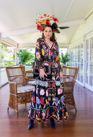 Woman wearing a long black dress with colourful prints and a headpiece sold and shipped rom Pizazz Boutique Nelson Bay