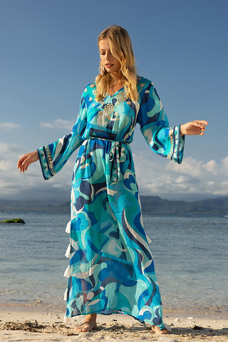 Woman wearing a blue dress standing on a beach, front view, showcasing resort wear from Pizazz Boutique Nelson Bay