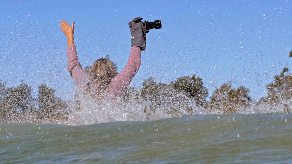 Deb Morris with underwater camera case splashing in wave