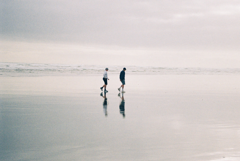 Two friends walking on a beach.
