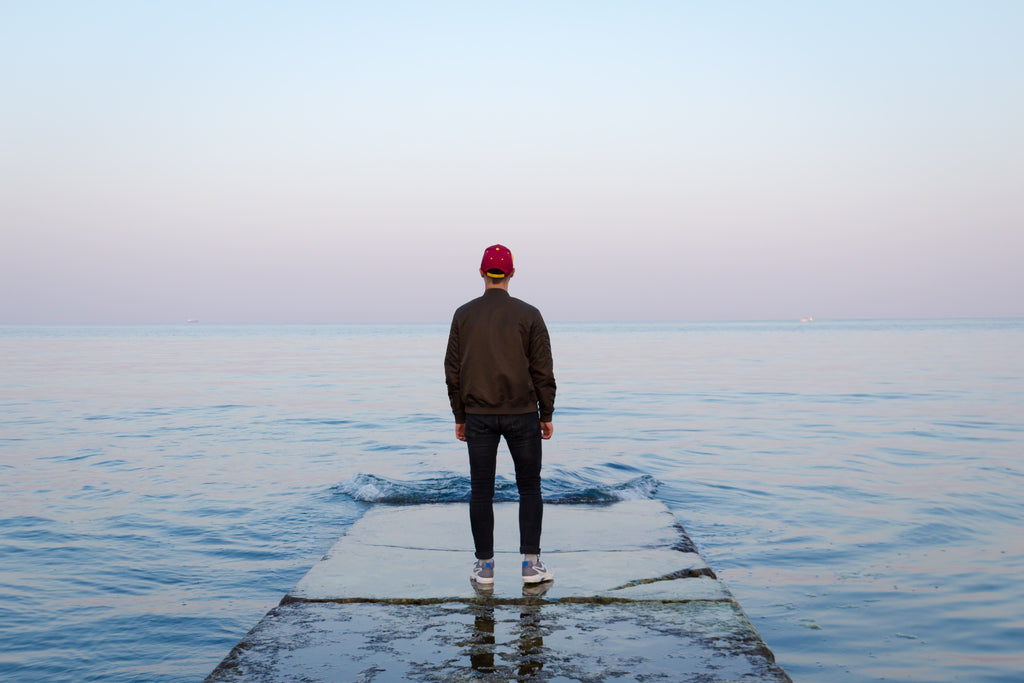 Man standing calmly in front of water.