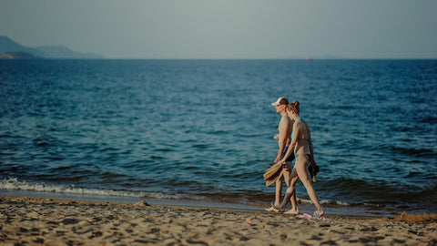 A couple walking on the beach near the waving sea