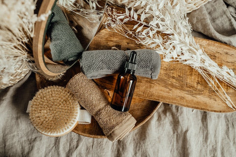 bottle with dropper and rolled face towels on a wooden tray