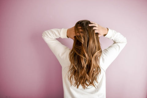 A shot of a woman's back and her hands in her hair