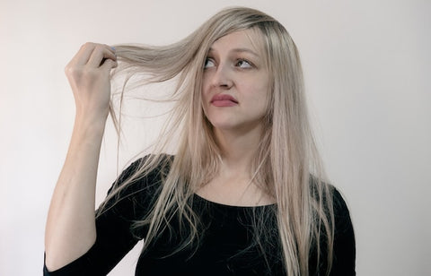 Blonde woman holding her hair with an unimpressed look on her face