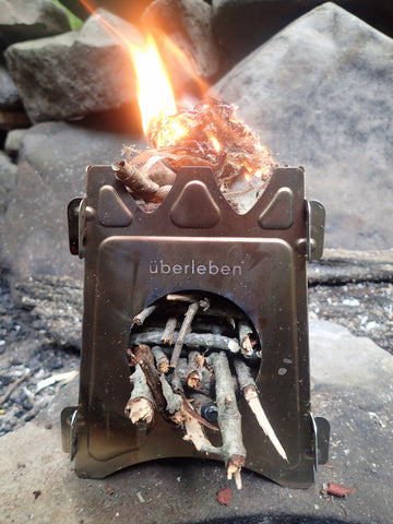 The versatile Überleben Stöker Flatpack Stove is used to as a small camp fire while camping.