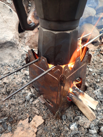 The Stöker Flatpack Stove being used to in the outdoors to heat a pot of water or coffee.