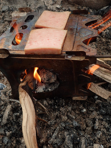 The Stöker Flatpack Stove turned on its side to function as a small griddle. This product allows outdoor enthusiasts to cook without the need for a fire pit.