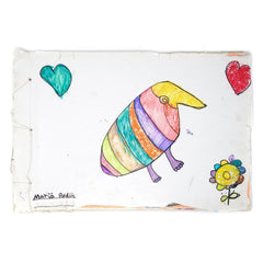 An artists book bound with white thread, signed in the bottom left by the artist. A rainbow-colored armadillo-like figure floats in the middle of the page, with a blue and a red heart in the upper corners, and a flower in the bottom right.