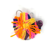 Bright, multi-colored yarn wrapped around a metal frame with two bedazzling gems attached.