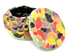 A glazed ceramic bowl with lid, overlaid with a loose scalloped pattern in a subtle palette of yellow, black, green and red.