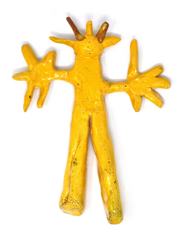 A ceramic figure, lying flat, arms and large hands outstretched, five antennae-like protrusions extending from its head, without facial features, glazed in goldenrod.
