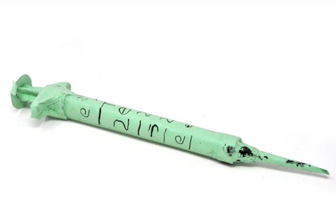 a celadon green paper syringe marked with number-like symbols in black ink