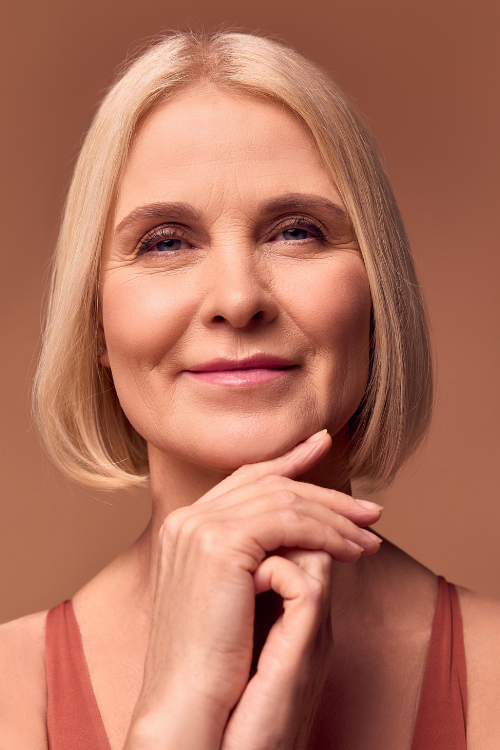 Blonde 60 something woman in a rust colored tank with a saggy brow