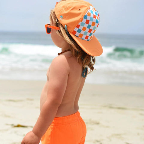 photo of young boy wearing a blue and orange checkered hat