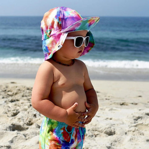 photo of a little boy at the beach wearing white sunglasses and a colorful hat