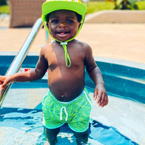 Young boy holding on to the railing of pool steps 