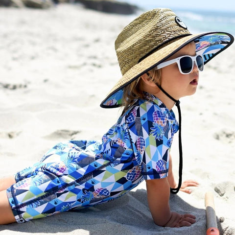 Young boy wearing sunsuit and straw hat at the beach