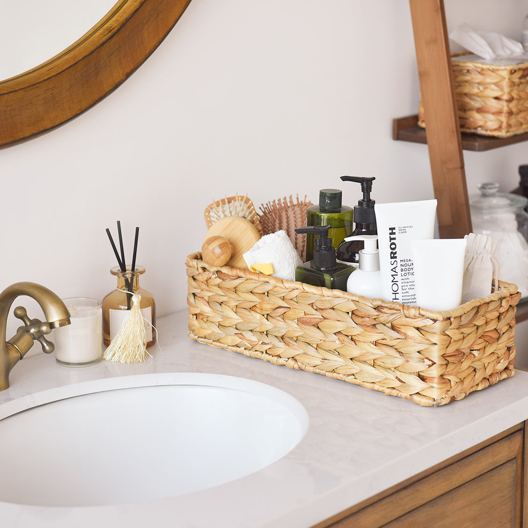 Handwoven wicker basket made from water hyacinth for toilet tank top holding toiletries on the sink.