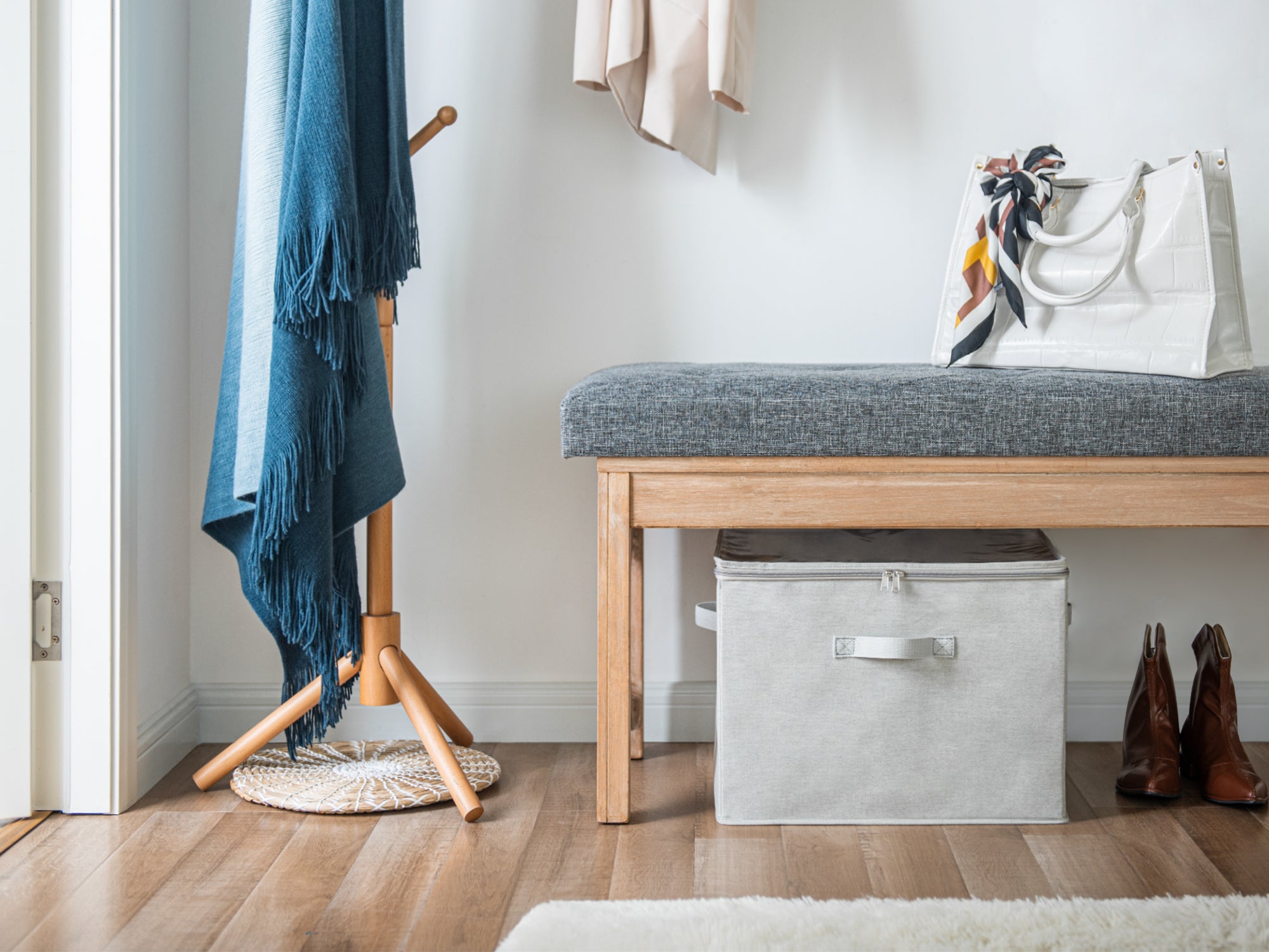 Gray shoe organizer under a shoe bench by the entryway