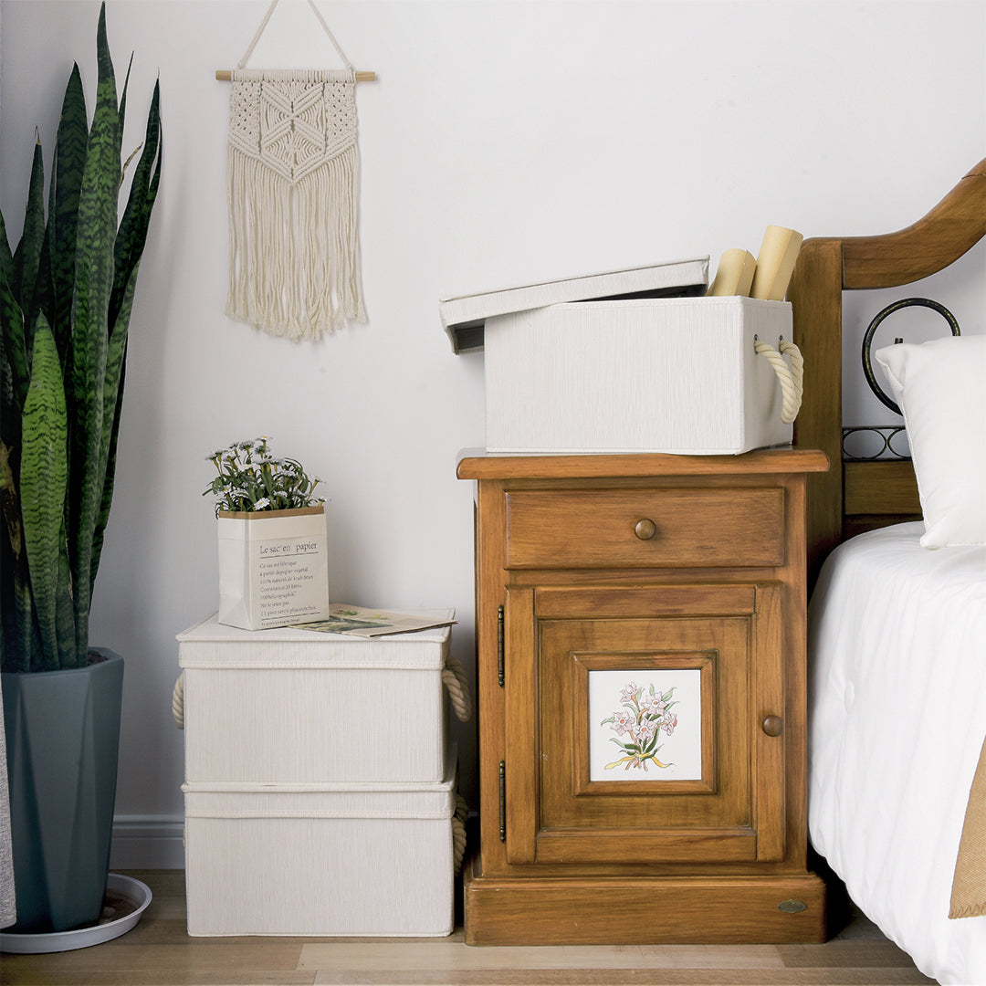 Fabric storage bins with lids stacked beside a nightstand in the bedroom