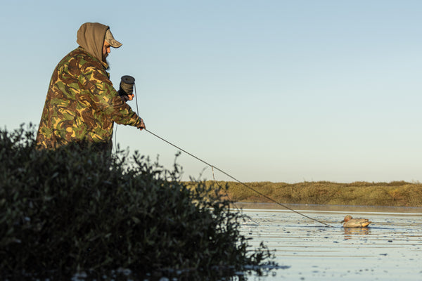 Un chasseur européen place des leurres dans l'eau au lever du soleil, prêt pour une expédition de chasse au gibier d'eau.