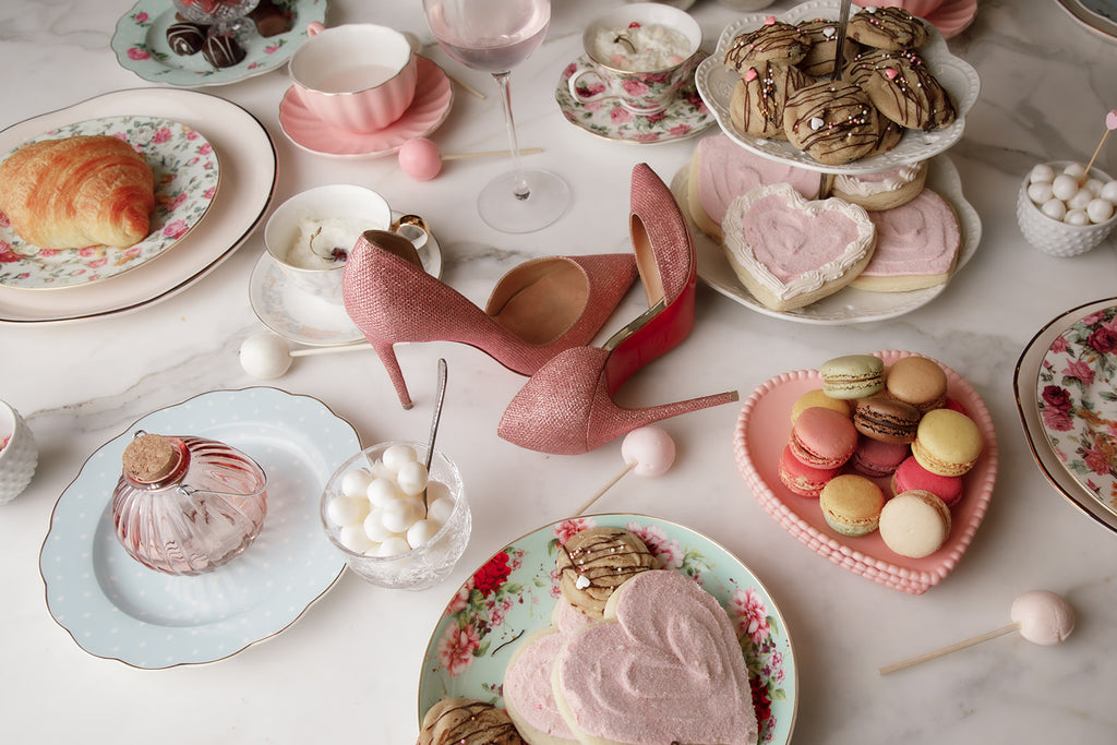 Overhead image of Rachel Parcell's counter filled with plates of cookies, candy, pastries, tea cups, and pink high heels