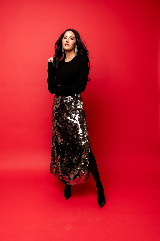 Rachel Parcell in photo studio with red backdrop wearing Black Crewneck Sweater and Silver Sequin Slit Skirt