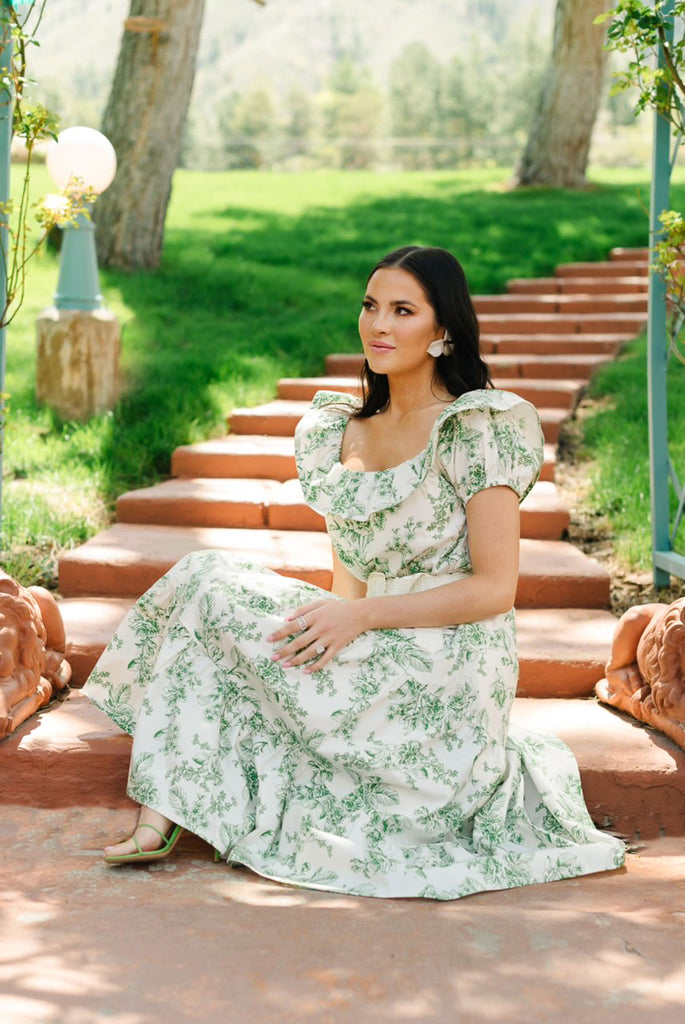 Rachel Parcell sitting, wearing RP Sage Toile Off Shoulder Ruffle Midi Dress