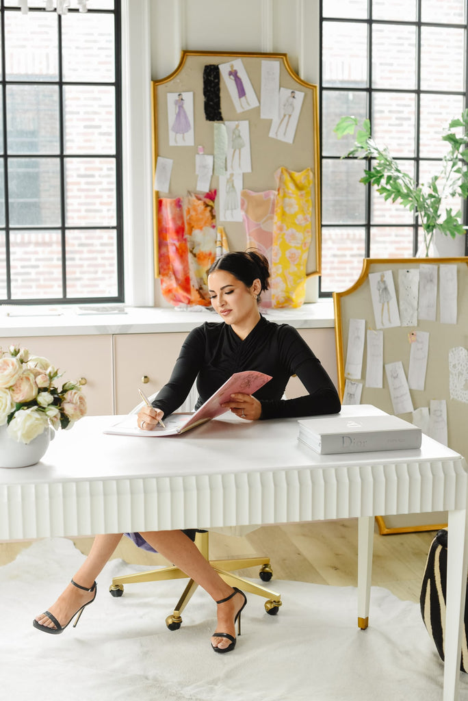 Rachel Parcell sitting at her desk writing in new RP x Blue Sky 2023 planner