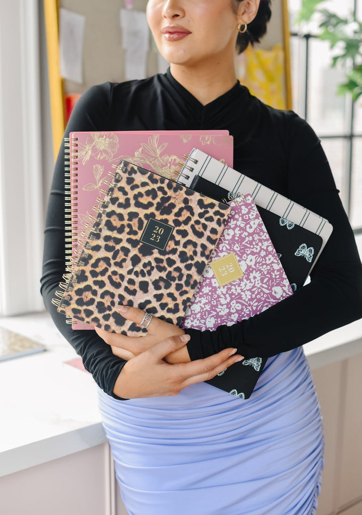 Rachel Parcell standing in her office holding stack of multiple different RP x Blue Sky 2023 Planners