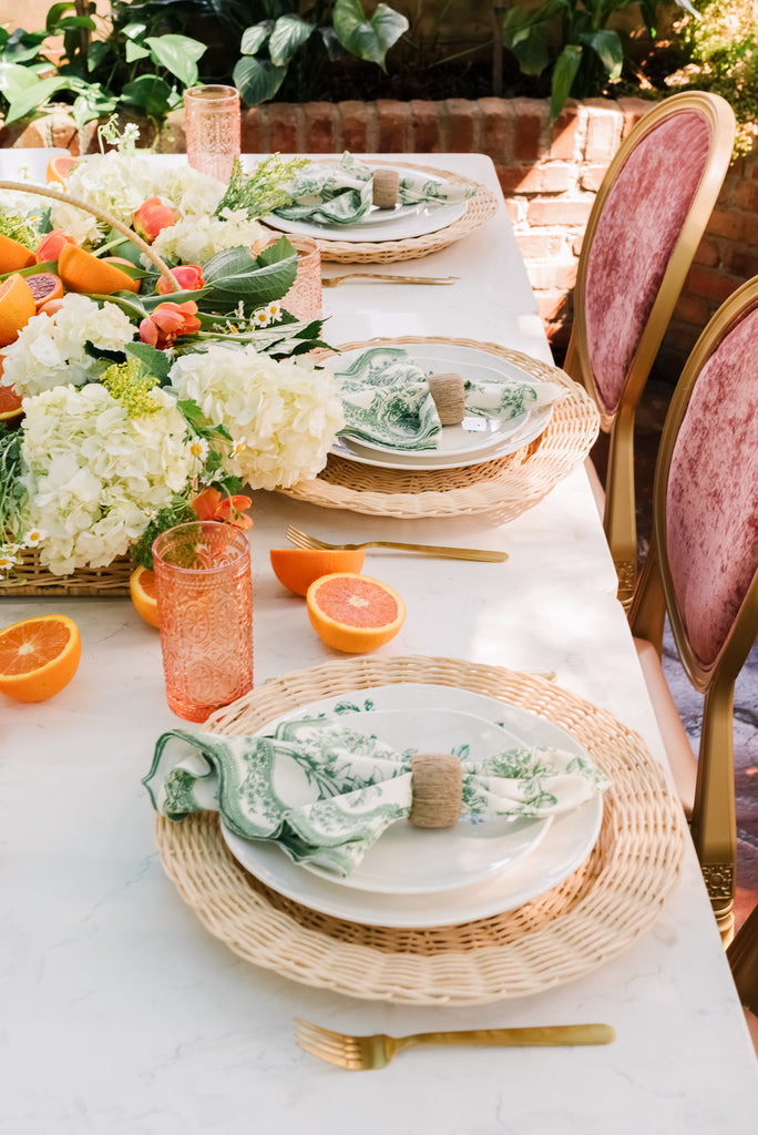 RP Summer Home 2022 Tablescape items: Large Wicker Tray, Wicker Chargers, Sage Toile Printed Linen Napkins, Raffia Napkin Rings, Forest Printed Melamine Dinner Plates, and Forest Printed Melamine Salad Plates