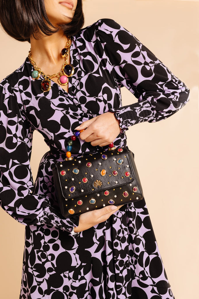 Model, Sabrina wearing new purple and black patterned RP dress, wearing jeweled Lele Sadoughi necklace and holding matching jeweled Lele Sadoughi Purse